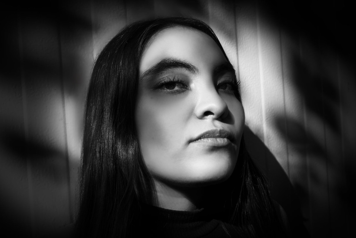 Fotografía primer plano en blanco y negro de una joven con sombras sobre su cara.